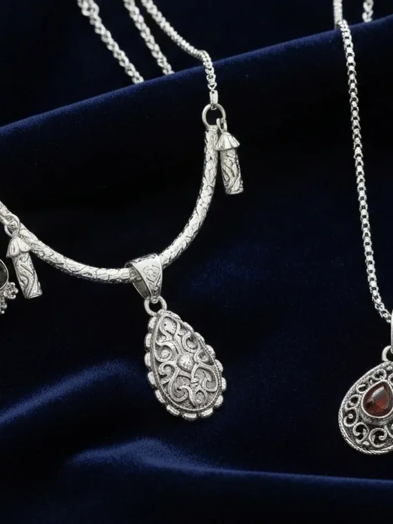 Silver pendant necklaces displayed on blue velvet